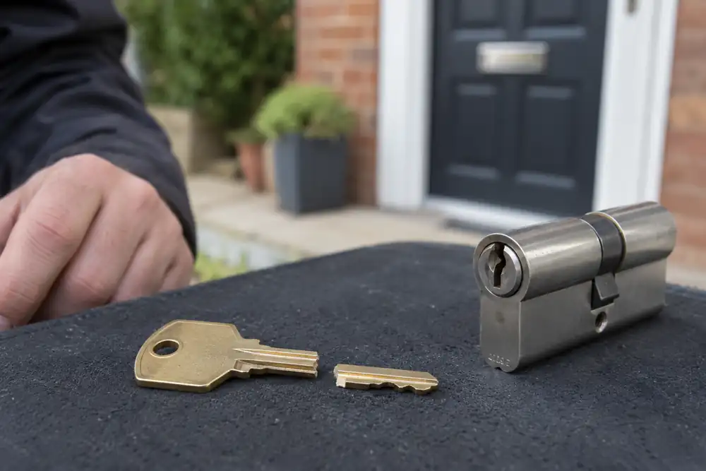 Locksmith inspecting a snapped key and door cylinder, macro view without an extraction technique.