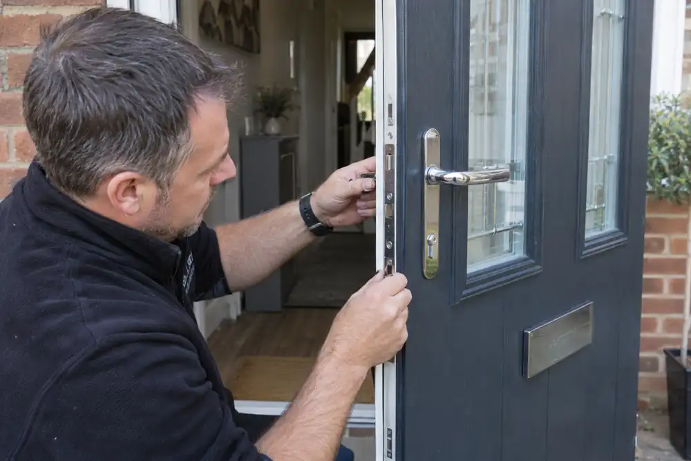 Locksmith checking lock and lever on open anthracite composite door.