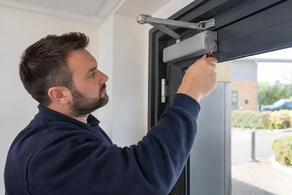 Technician checking surface mounted overhead door closer on commercial door.