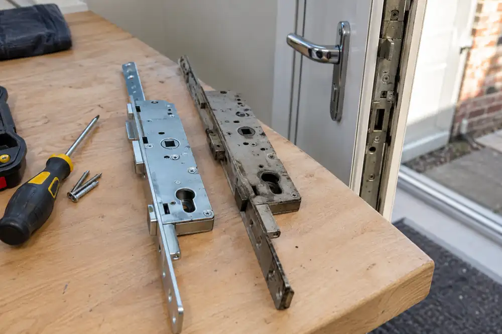 Multipoint gearbox and replacement locking hardware on a workbench.