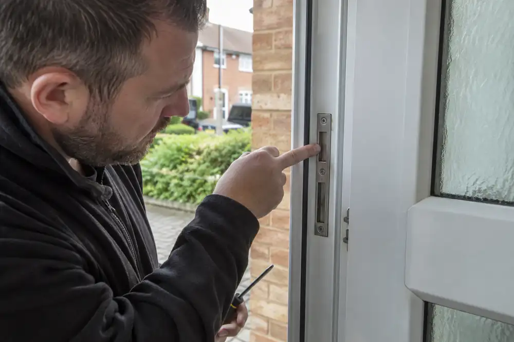 Locksmith inspecting metal strike keeps on a uPVC frame.