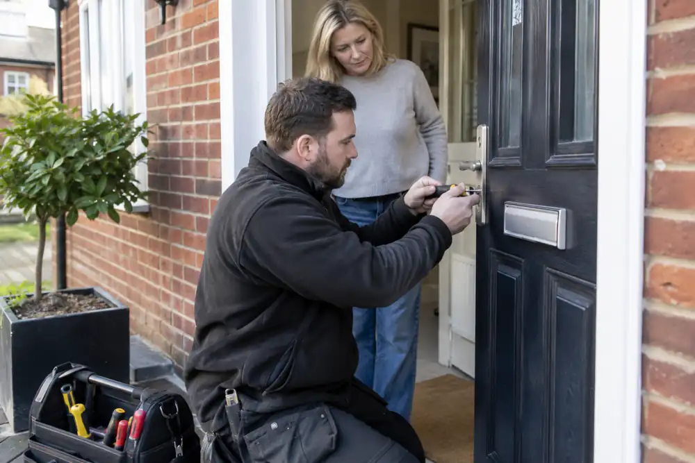 Locksmith at a UK front door with a compact tool bag, householder present.
