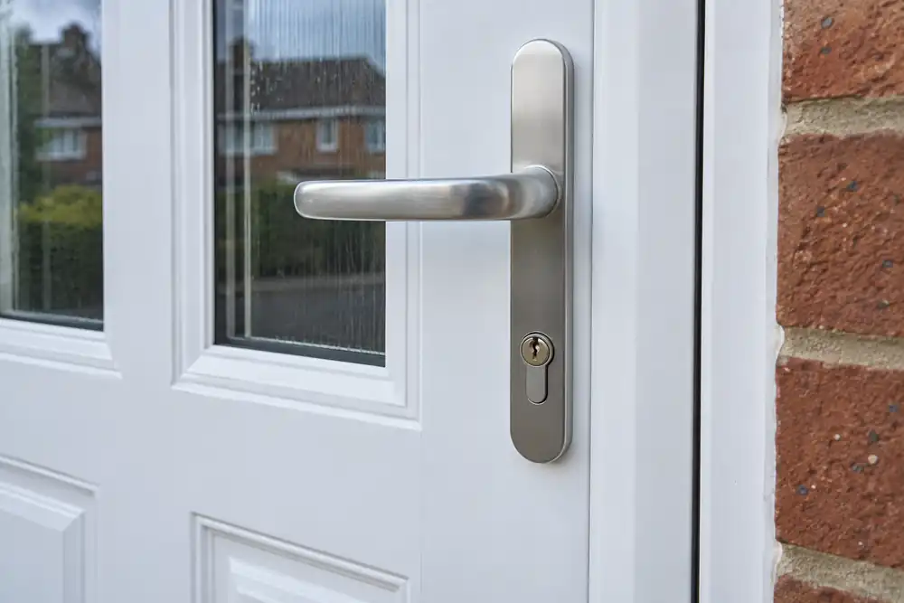 Completed euro-cylinder replacement with brushed-metal handle on a closed white door.