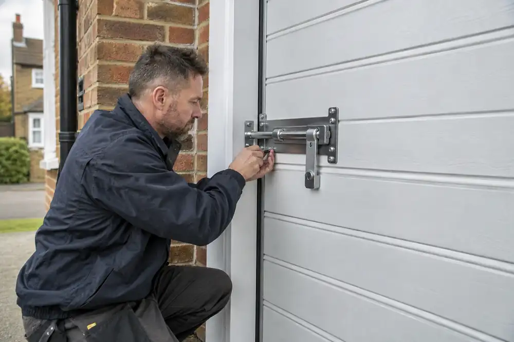 Locksmith assessing additional garage door security hardware on a domestic garage.