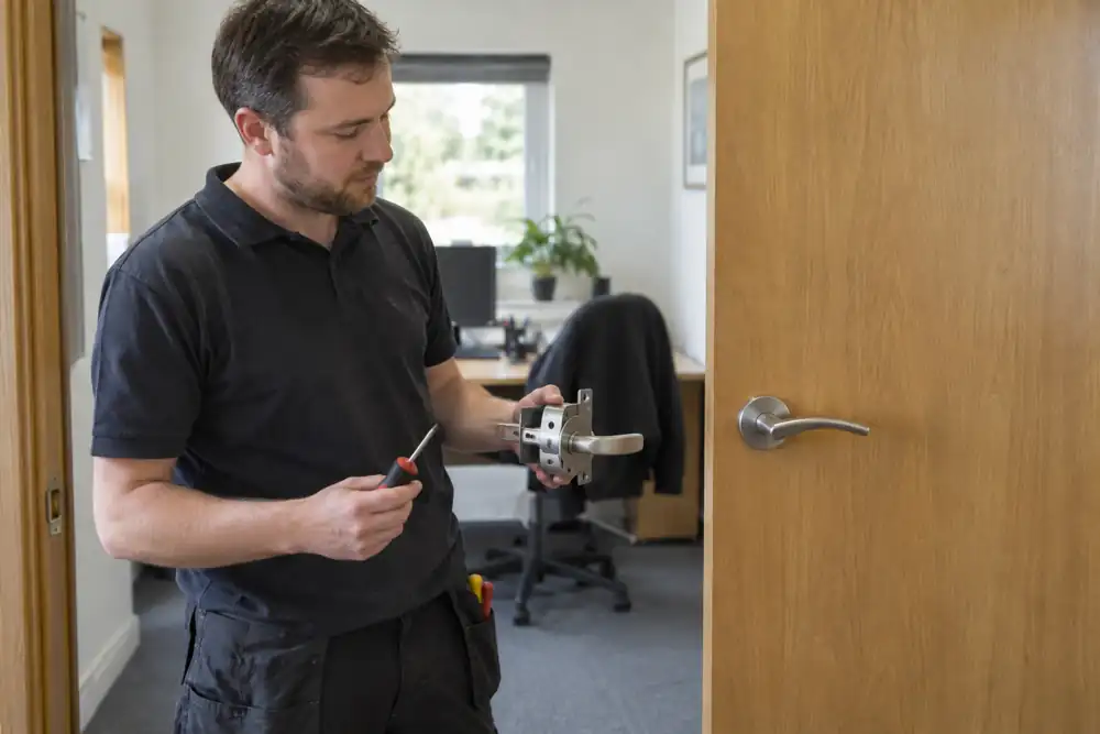 Locksmith replacing a simple lock on an open interior office door.