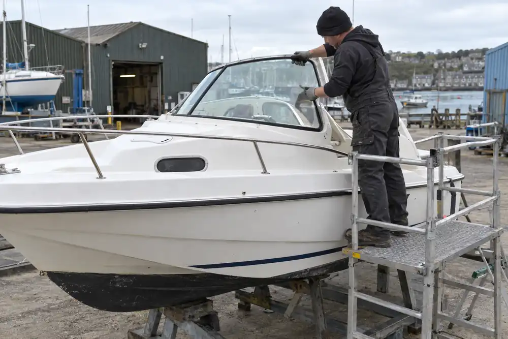 Technician installing a motorboat cabin windscreen at a boatyard