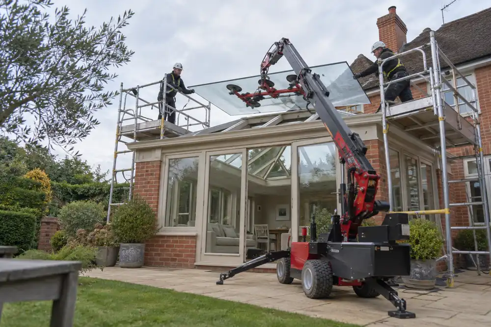 Team replacing an orangery roof glass panel using supported lifting