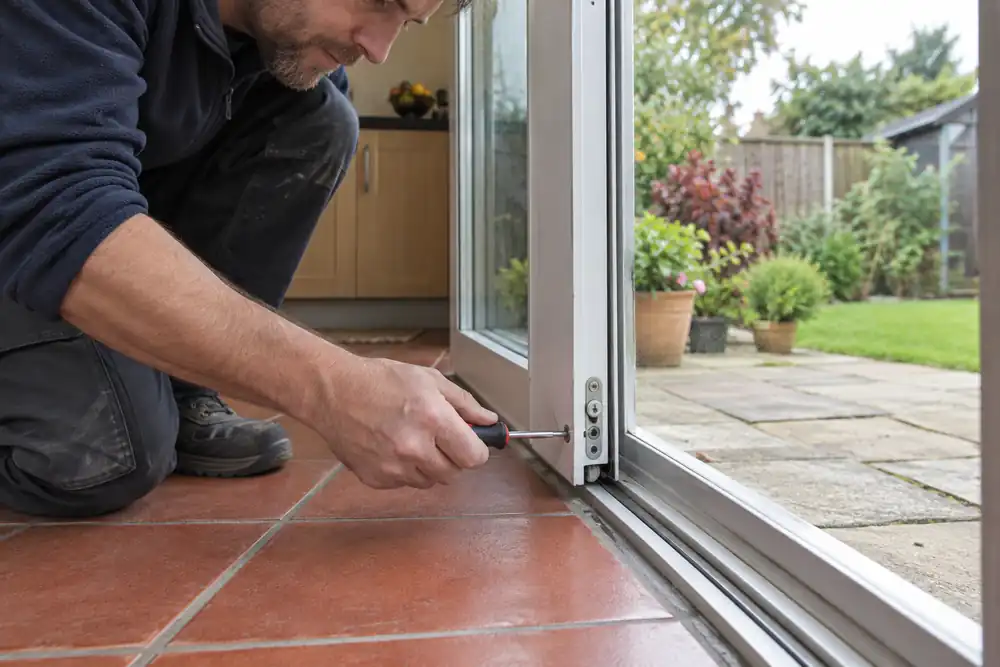 Technician adjusting the lower frame of a sliding patio door