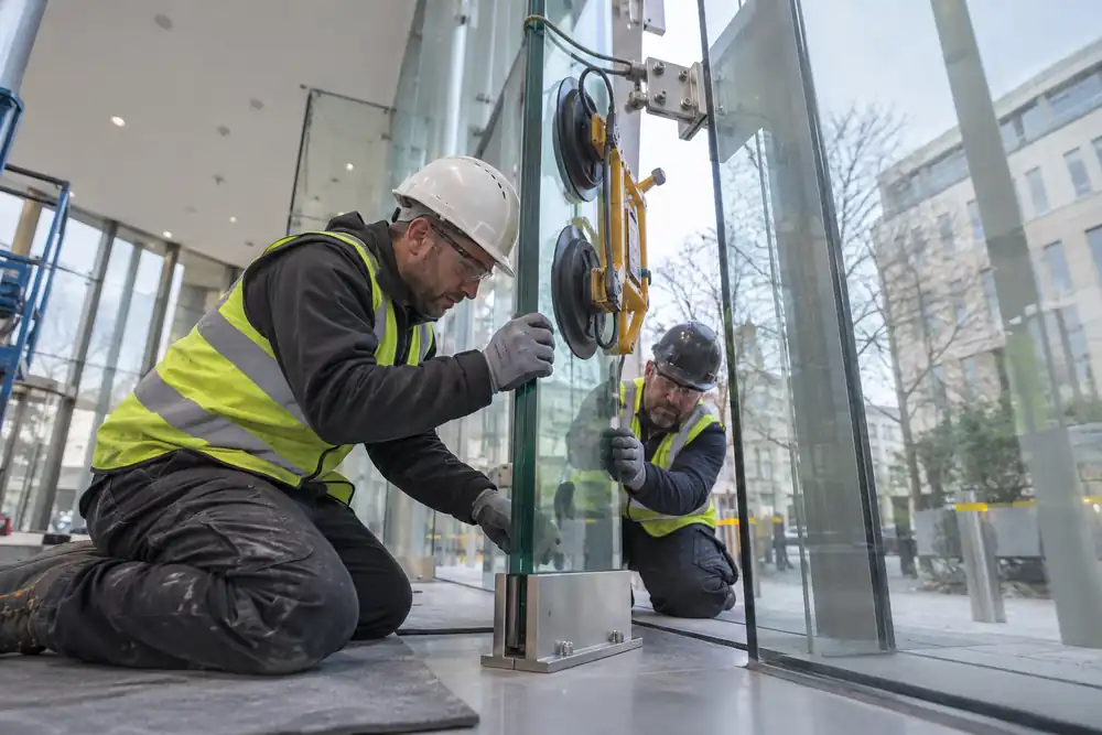 Installers aligning a supported structural glass fin in a lobby