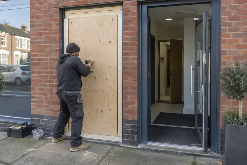 Carpenter fitting a temporary plywood closure in a vacant doorway